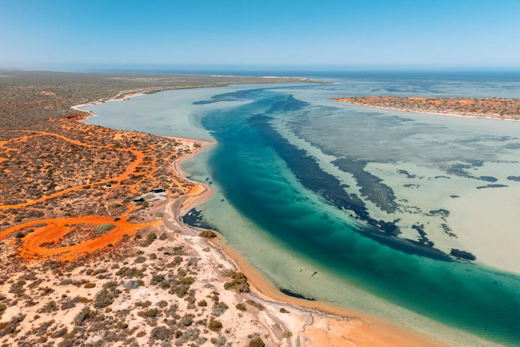 Spektakuläre Drohnenaufnahme der Big Lagoon im Francois Peron Nationalpark, Westaustralien: Der krasse Kontrast zwischen der rostroten Erde, den weißen Sandstränden und dem türkisfarbenen Wasser der Shark Bay.