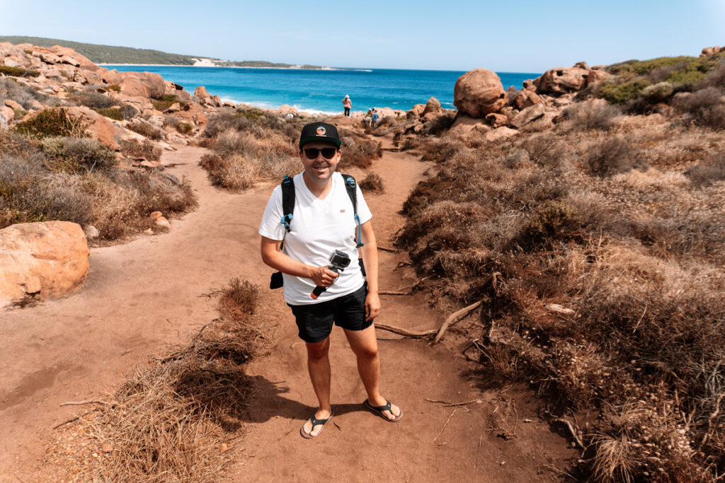 Mario von Auszeit Abenteuer steht vor dem Injidup Natural Spa Rote Felsen im Hintergrund türkisblaues Meer