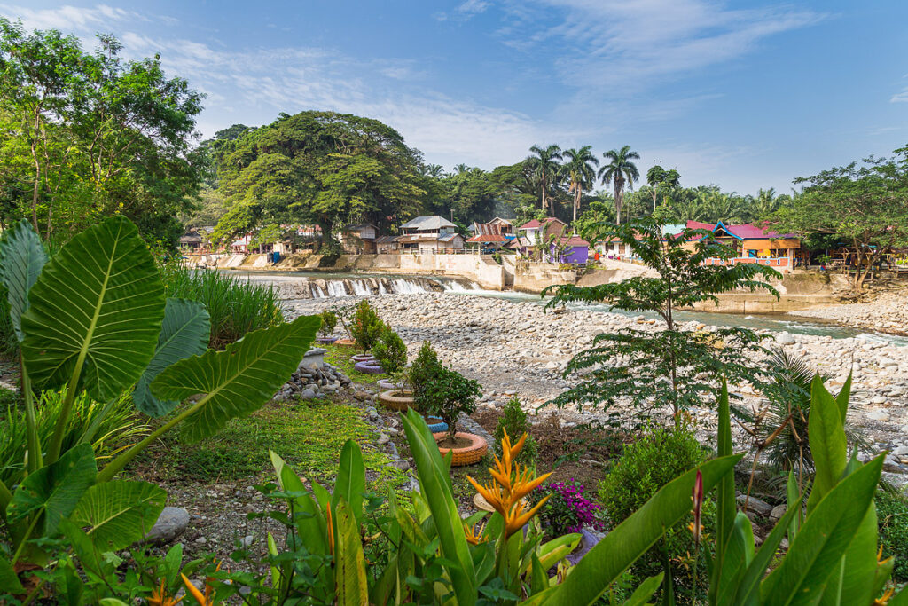 Bohorok Fluss in Bukit Lawang am Rande des Gunung Leuser Nationalparks Sumatra mit bunten Guesthouses und tropischer Vegetation