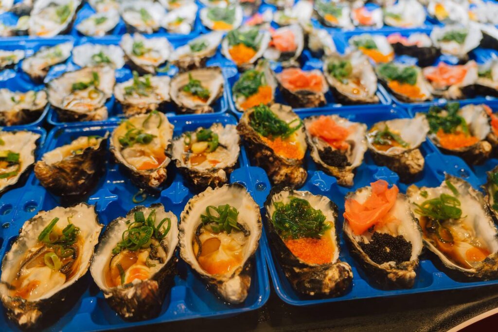 Frisch geöffnete Austern, appetitlich angerichtet in blauen Schalen und garniert mit buntem Seealgensalat, Rogen und Frühlingszwiebeln auf dem New Sydney Fish Market.