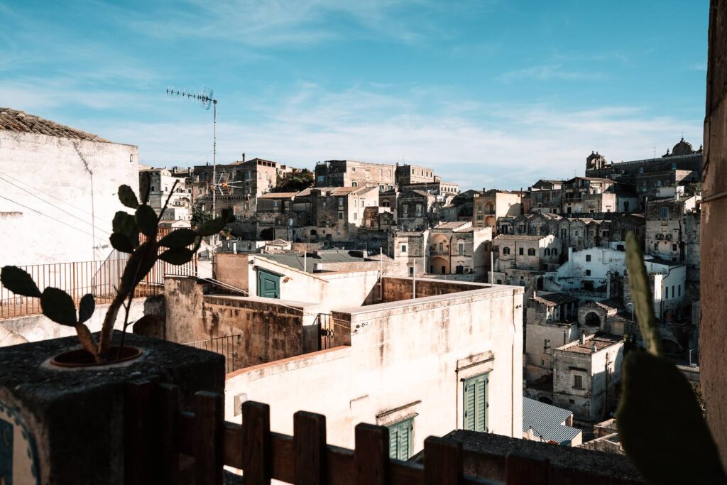 Die archaische Felsgewalt von Matera: Unzählige alte Steingebäude drängen sich unter einem blauen Himmel aneinander.