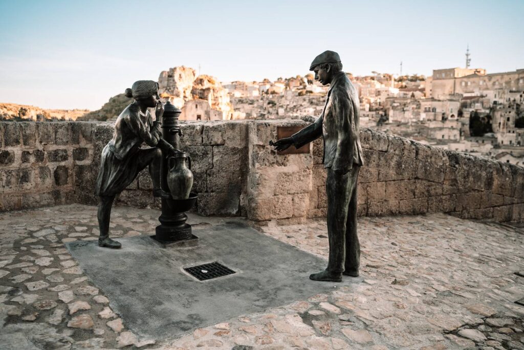 Das romantische Bronzedenkmal Fontana dell'Amore in den Sassi von Matera, das eine historische Liebesgeschichte am Brunnen darstellt.