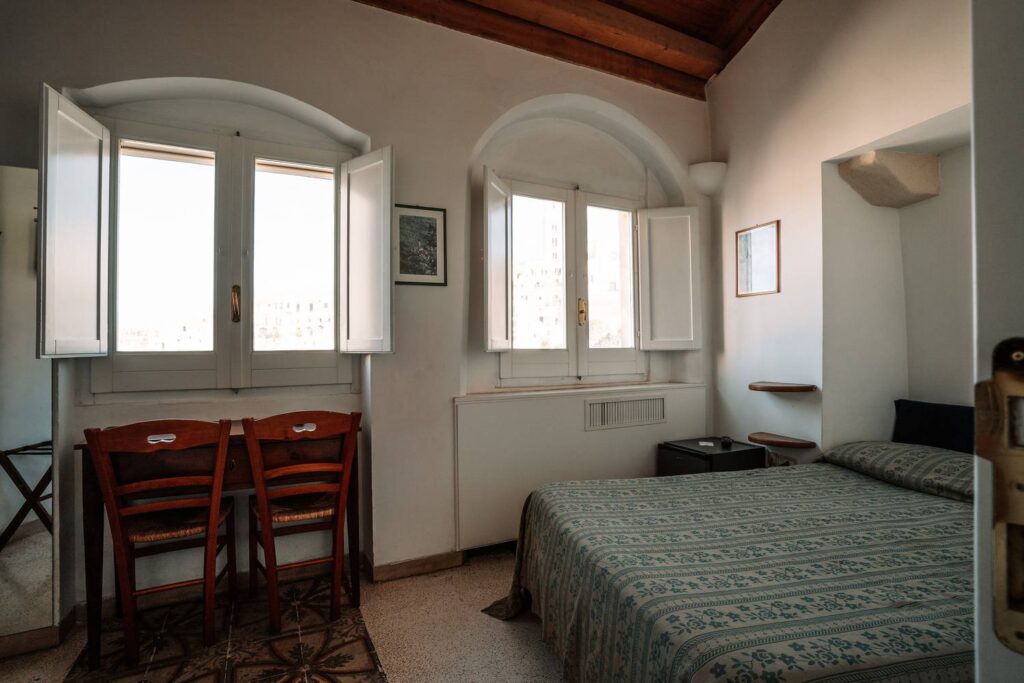 Urige Einrichtung in einem historischen Steingewölbe-Zimmer in Matera mit einem gemütlichen Bett unter einer runden Steindecke.